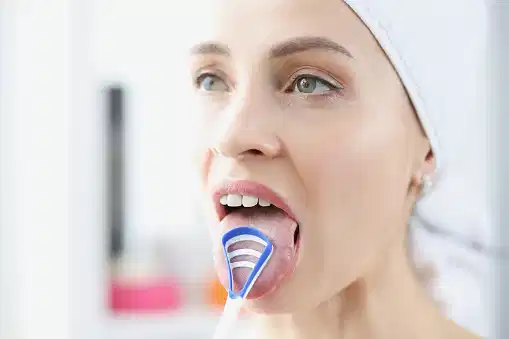 mujer cepillando la lengua para prevenir el mal aliento