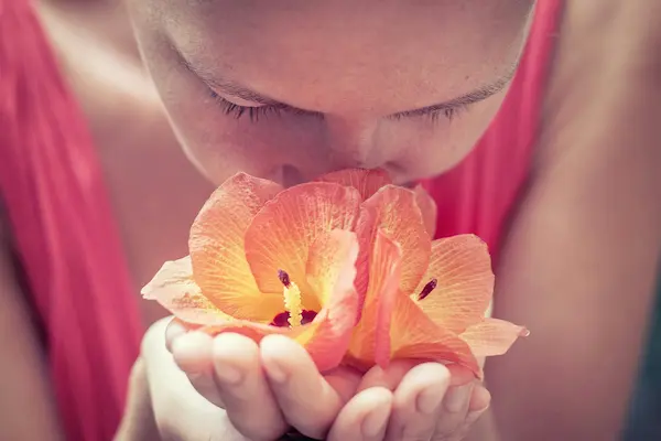 mujer oliendo flores.