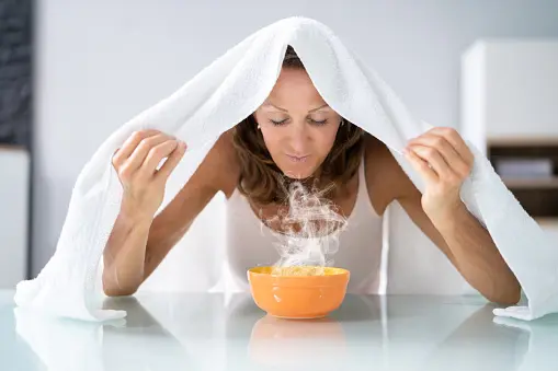 mujer aspirando vapor para limpiar su nariz